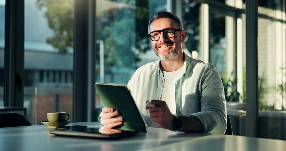Hombre sonriente leyendo en una tableta