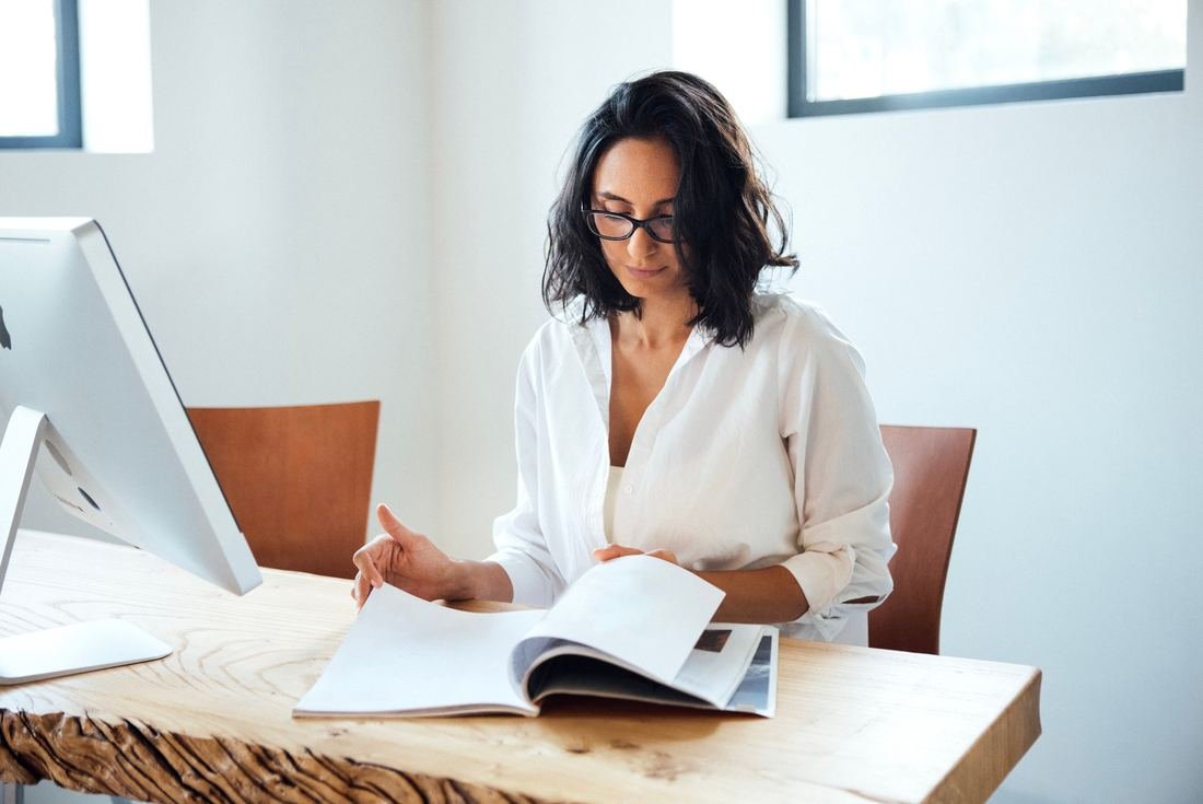 Mujer leyendo una revista sobre su escritorio